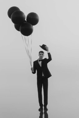 Suda elinde balonlar olan takım elbiseli bir adamın gerçek üstü portresi.