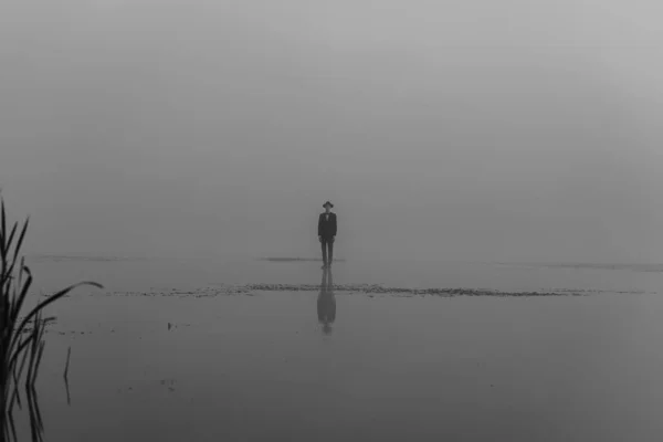 Retrato surreal de um homem de terno com um chapéu em pé na água — Fotografia de Stock