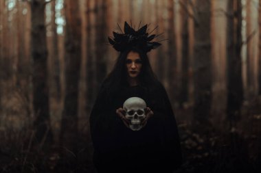 Kara Korkunç Cadı elinde ölü bir adamın kafatasını tutuyor.