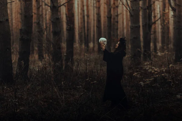 Czarna straszna wiedźma z czaszką w rękach martwego człowieka — Zdjęcie stockowe