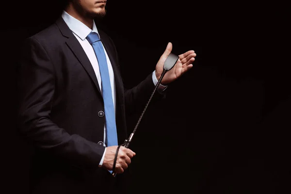 Male dominant businessman in a suit holding a leather whip Flogger for domination