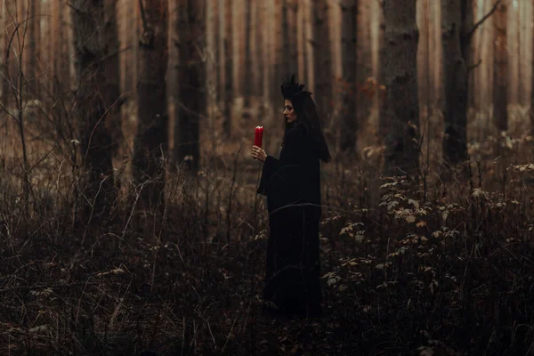 Темная ужасная ведьма со свечами в руках исполняет оккультный мистический ритуал — стоковое фото