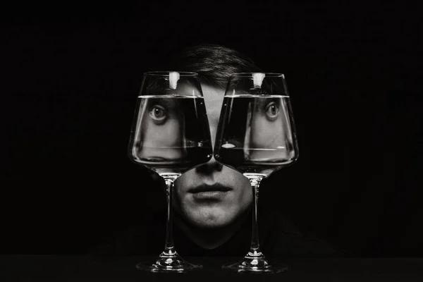 portrait of a strange man looking through two glasses of water