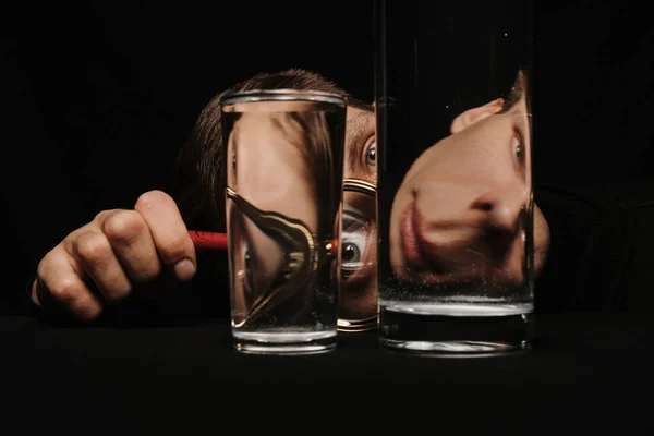 Чоловік дивиться через збільшувальний келих і склянки води — стокове фото