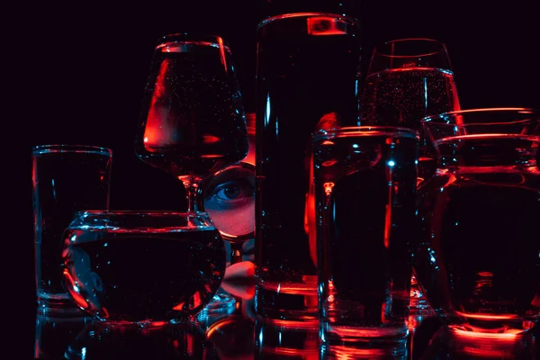 Man tittar genom ett förstoringsglas och glas glas glas med vatten — Stockfoto