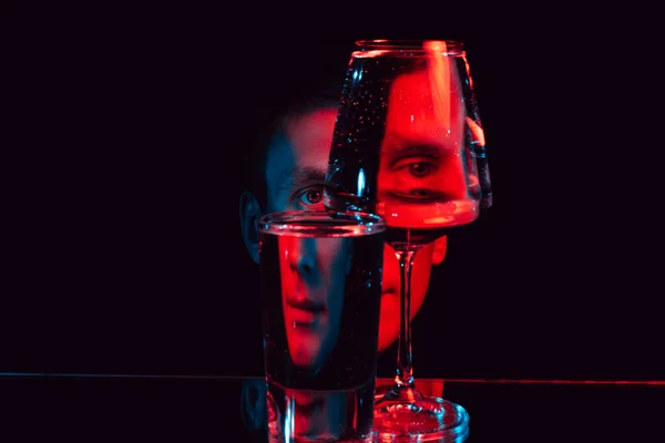 Człowiek patrząc przez szklane szklanki wody z odbiciami i zniekształceniami — Zdjęcie stockowe