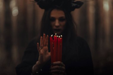 Elinde mumlarla karanlık, korkunç bir cadı mistik bir ayin yapıyor.
