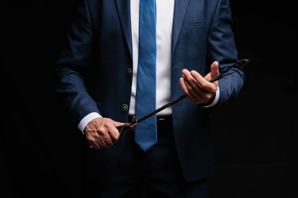 Male dominant businessman in a suit holding a leather whip Flogger for domination