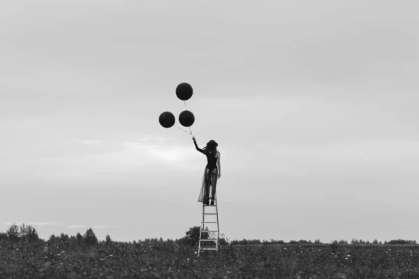 Surrealistische foto van een meisje in een hoed met ballonnen in haar hand — Stockfoto
