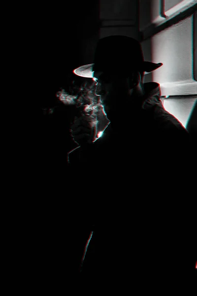 Sombre silhouette dramatique d'un homme coiffé d'un chapeau Fumer une cigarette dans la rue la nuit dans le style Noir — Photo