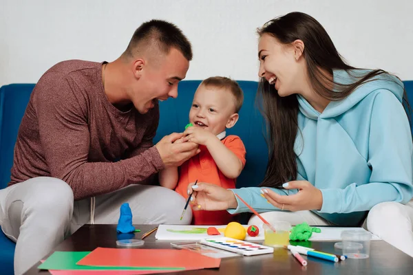 Famiglia sono impegnati nel lavoro creativo e divertirsi a casa. Mamma, papà e figlio piccolo — Foto Stock