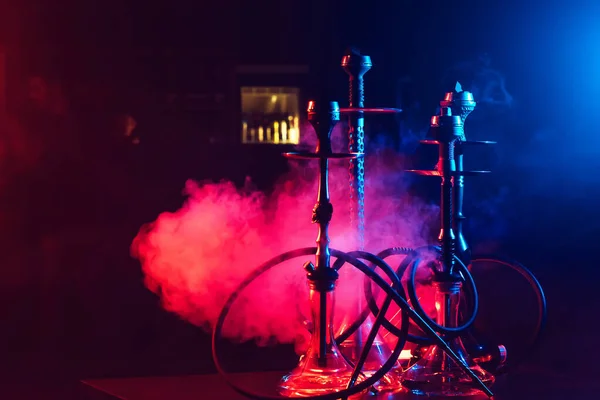 Hookahs with shisha coals in bowls against a background of smoke with neon lighting — Stock Photo, Image