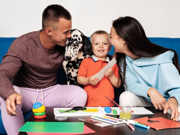 Giovane famiglia caucasica con un cane fare lavoro creativo a casa — Foto Stock