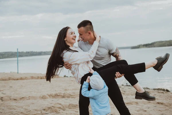 Jovem família feliz se divertindo na areia na praia — Fotografia de Stock