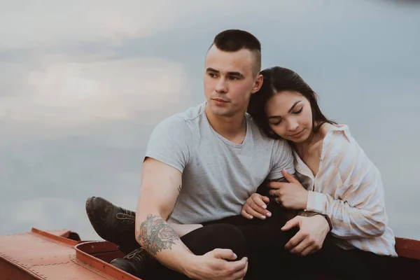 Joven pareja romántica enamorada sentada en un bote junto al agua —  Fotos de Stock