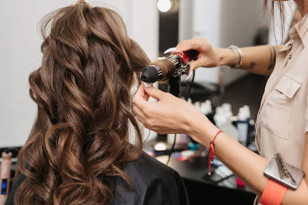 Stylist teszi fürtök curling lány hosszú barna haj — Stock Fotó