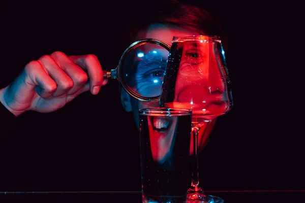 Portret van een lachende psychopaat die door een vergrootglas en glazen bril kijkt — Stockfoto