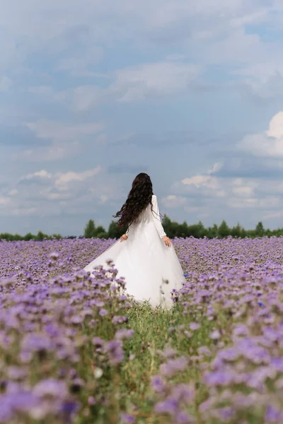 Panna młoda wirująca na polu kwiatów w dniu ślubu — Zdjęcie stockowe