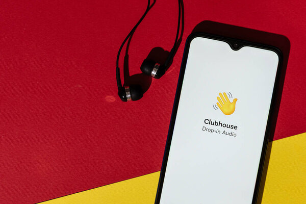VICHUGA, RUSSIA - FEBRUARY 20, 2021: Logo of new trending app Clubhouse drop-in audio on smartphone screen and headphones