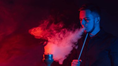 Erkek tiryaki nargile tüttürür ve bir duman bulutu çıkarır.