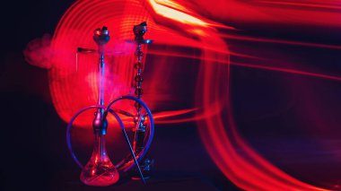 Masada kırmızı ve mavi neon ışıkları olan kaselerde shisha kömürleri olan dumanlı doğu hookahları.