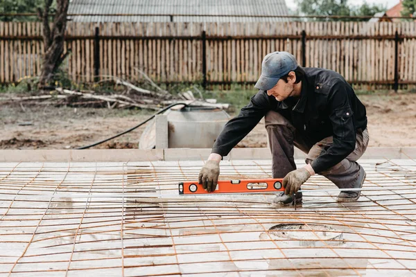 male worker measures the construction level of rebar for the foundation