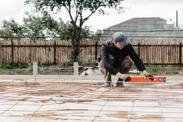 male worker measures the construction level of rebar for the foundation