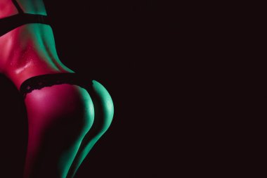 Sexy ass of woman in panties with drops of water and sweat on her body. Slim beautiful female body in underwear with neon light