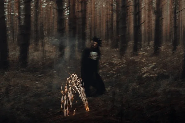 Verschwommene Silhouette einer bösen schwarzen Hexe mit Totenkopf in den Händen, die ein okkultes satanisches Ritual ausführt — Stockfoto