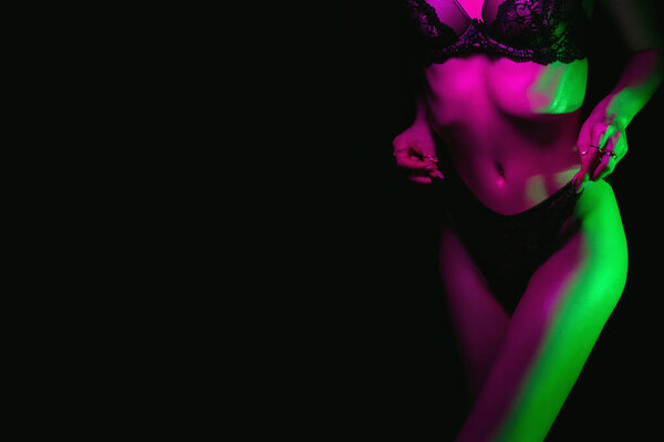 Slim figure of beautiful sexy girl in panties and bra. Body skinny fitness women underwear on dark background with neon light. Copy space