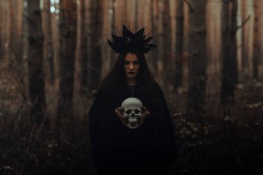 Kara Korkunç Cadı elinde ölü bir adamın kafatasını tutuyor.