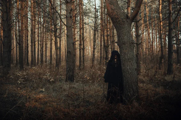 Retrato escuro de uma bruxa terrível em um terno preto na floresta — Fotografia de Stock