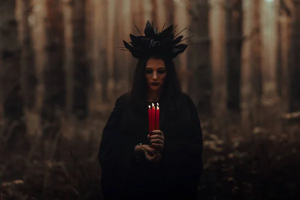 Черная ужасная ведьма держит свечи в руках — стоковое фото
