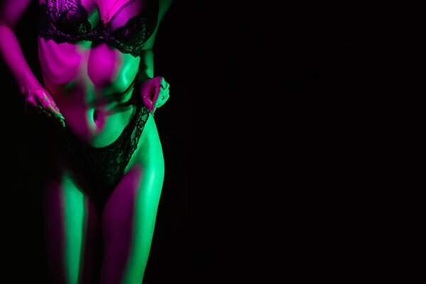 Figure of a thinning girl in her underwear. Sexy womans body with neon light on dark background. Copy space