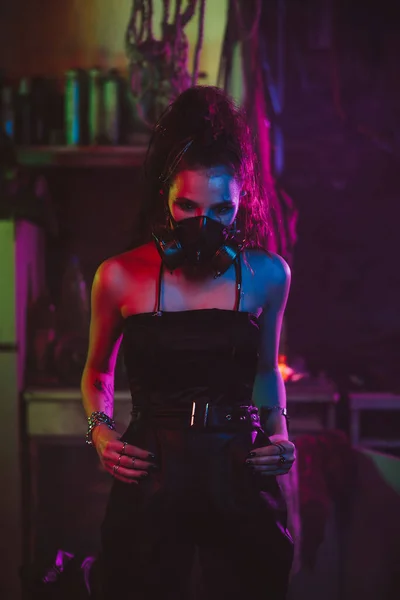 Chica en estilo cyberpunk en un traje de máscara de gas con una luz de neón por la noche — Foto de Stock