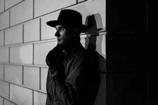 Portrait sombre d'un homme en imperméable avec un chapeau la nuit dans la rue — Photo