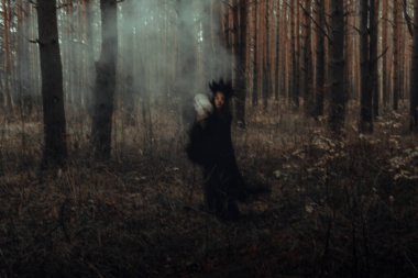 Elinde kafatasıyla şeytani bir kara cadının bulanık silueti şeytani bir şeytani ayin gerçekleştiriyor.