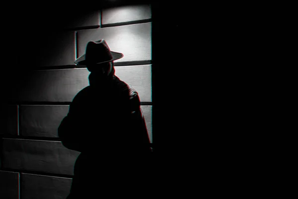 Silhouette sombre d'un homme en imperméable avec un chapeau la nuit — Photo