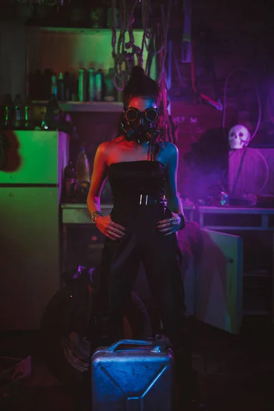 Soldado menina em estilo cyberpunk com uma máscara de gás e óculos com iluminação de néon na garagem. Estilo Steampunk — Fotografia de Stock