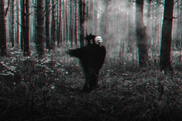 Розмитий силует злої чорної відьми з черепом у руках, що виконує окультний сатанинський ритуал — стокове фото