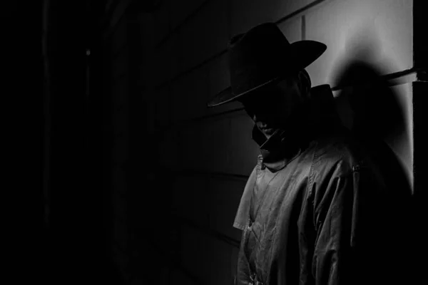 Silueta oscura de un hombre en un impermeable con un sombrero en la noche —  Fotos de Stock