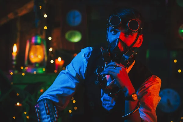 赛博朋克世界末日后的科幻游戏。一个戴眼镜和防毒面具的男人在一个有霓虹灯的车间里 — 图库照片