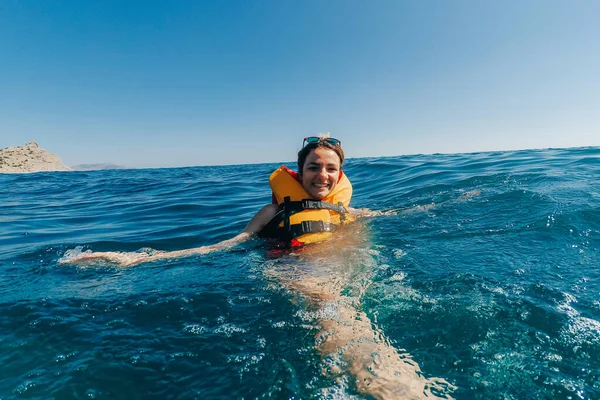 Szczęśliwa dziewczyna w kamizelce ratunkowej pływa w wodzie w morzu — Zdjęcie stockowe