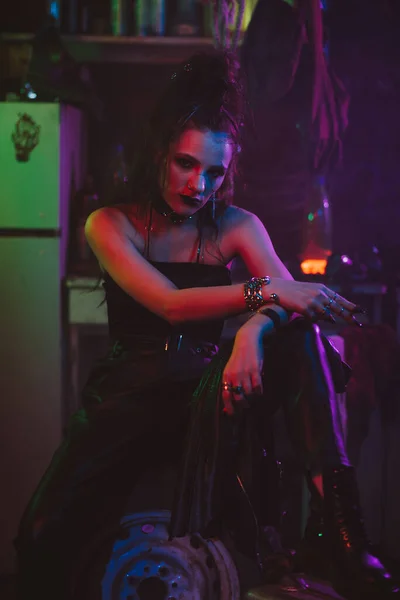 Chica en un traje futurista cyberpunk fuma un cigarrillo con una luz de neón en el garaje. Estilo Steampunk — Foto de Stock