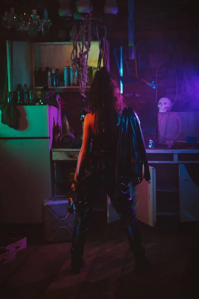 Girl in a cyberpunk suit with a neon light in the garage. Steampunk cosplay in the post-apocalyptic style — Stock Photo, Image