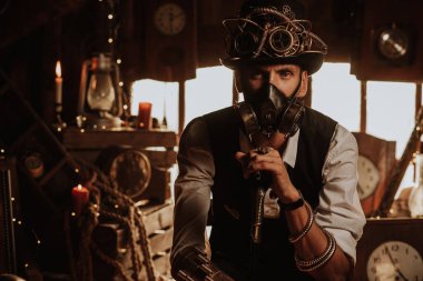 Steampunk kıyafetli, silindir şapkalı, gözlüklü ve gaz maskeli bir mühendis.