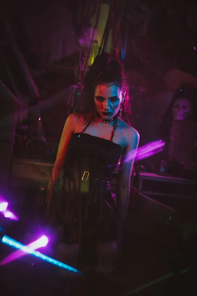 Flicka i en cyberpunk kostym med ett neonljus i garaget. Steampunk cosplay i postapokalyptisk stil — Stockfoto
