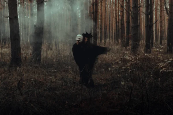 Wazig silhouet van een kwade zwarte heks met een schedel in haar handen die een occult satanisch ritueel uitvoert — Stockfoto