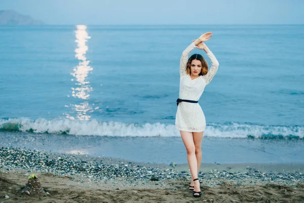 Chica caucásica posando junto al mar en la playa por la noche — Foto de Stock