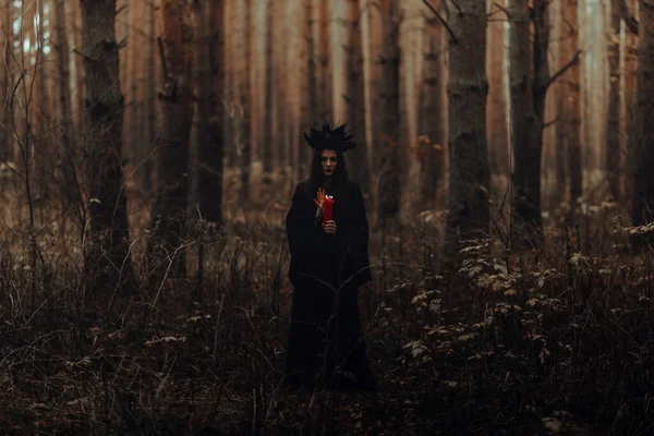 Strega in costume nero esegue incantesimi scuri con candele — Foto Stock